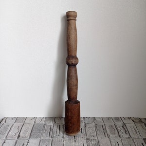 May include: A wooden pestle with a rounded head and a long, slender handle. The pestle is brown and has a smooth, polished finish.