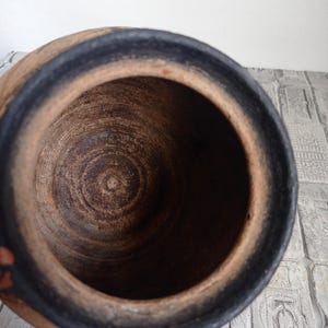 May include: The inside of a terracotta pot with a black rim. The pot is empty and has a rough, textured surface.