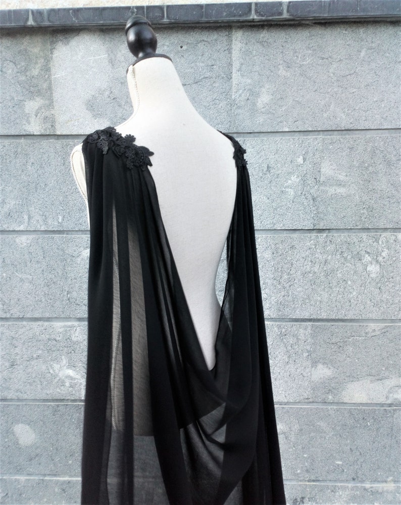 Pu&ograve; includere: Una cappa nera di chiffon con delicati dettagli in pizzo sulle spalle. La cappa &egrave; drappeggiata su un manichino bianco e ha la schiena bassa.