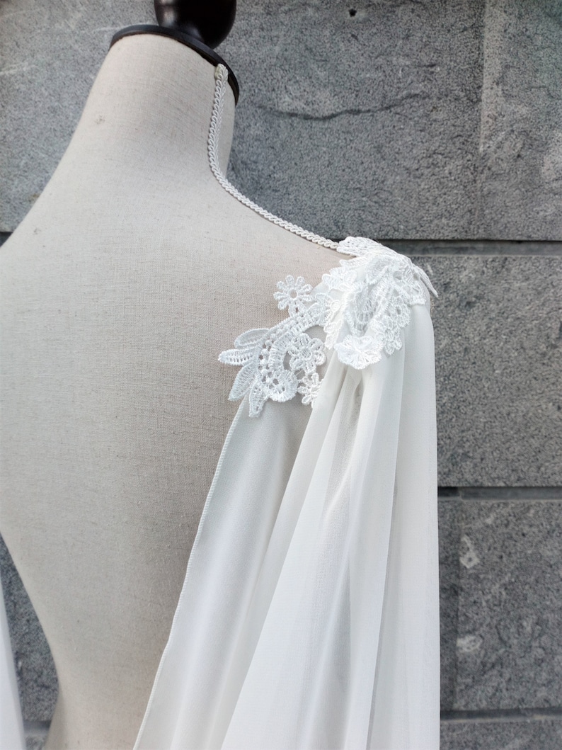 Pu&ograve; includere: Cappotto da sposa in chiffon bianco con dettagli in pizzo delicati sulla spalla.