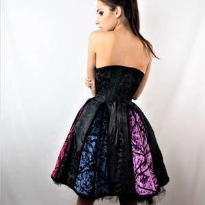 May include: A black strapless dress with a fitted bodice and a full skirt. The skirt is made of different colored fabrics, including black, blue, and pink.