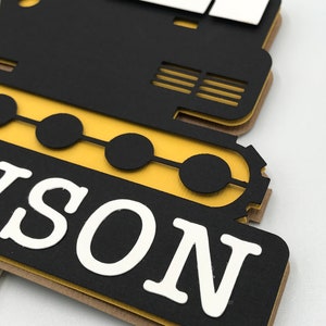 May include: Black and yellow construction vehicle cutout with the name "NASON" in white letters.