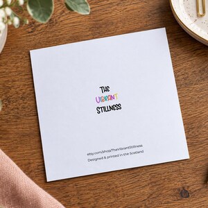 May include: A square white greeting card featuring the text The Vibrant Stillness in black, with the word Vibrant in multicolored letters. Below, the text reads etsy.com/shop/TheVibrantStillness and Designed & printed in the Scotland.