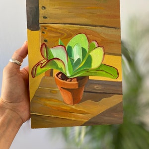 Puede incluir: Pintura al &oacute;leo de una planta suculenta en una maceta de terracota. La planta tiene hojas verdes con bordes rojos. La pintura est&aacute; ambientada sobre un fondo de madera con sombras.