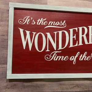 Puede incluir: Un letrero de madera rojo con letras blancas que dice "It's the most WONDERFUL Time of the".