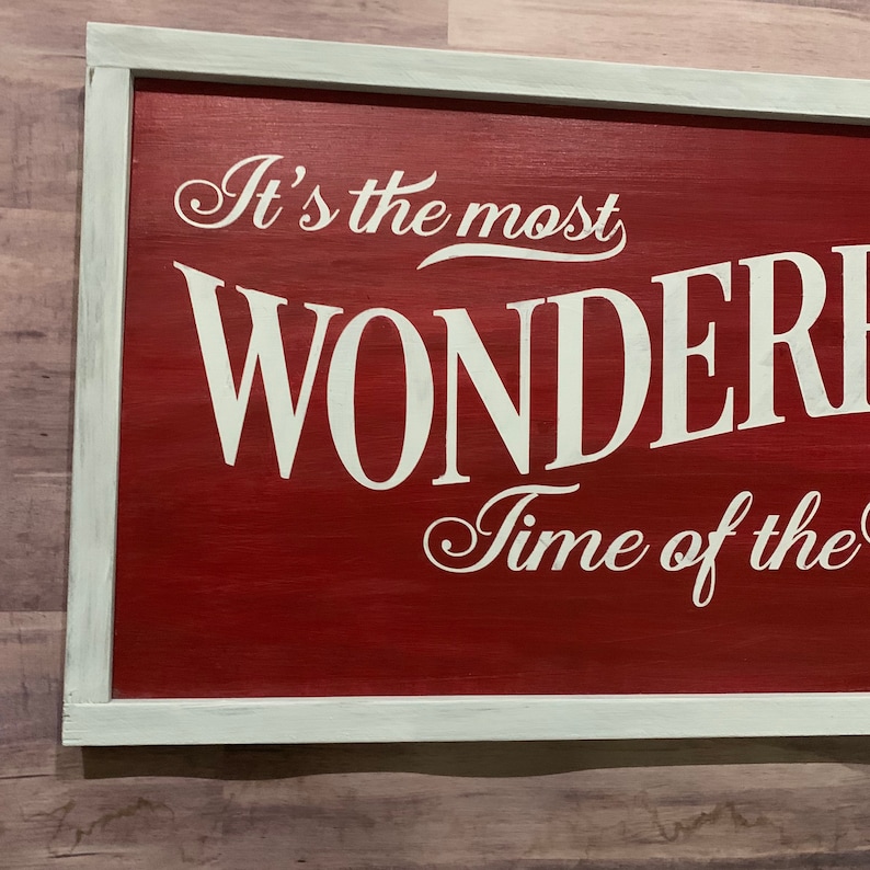 Puede incluir: Un letrero de madera rojo con letras blancas que dice "It's the most WONDERFUL Time of the".