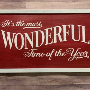 Puede incluir: Un letrero de madera rojo con letras blancas que dice "It's the most WONDERFUL Time of the Year".