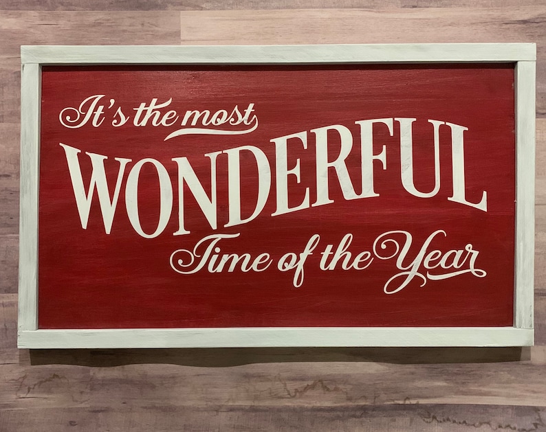 Puede incluir: Un letrero de madera rojo con letras blancas que dice "It's the most WONDERFUL Time of the Year".