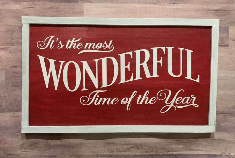 Puede incluir: Un letrero de madera rojo con letras blancas que dice "It's the most wonderful time of the year". El letrero est&aacute; enmarcado con un borde blanco.