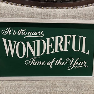 Puede incluir: Se&ntilde;al verde con marco blanco y el texto "It's the most WONDERFUL Time of the Year" en letras blancas.