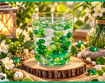 May include: A clear glass candle filled with a gel wax base containing various shades of green glass beads and white pearl-like spheres. A single white wick is centred in the top of the candle, which sits on a circular wooden slice base.