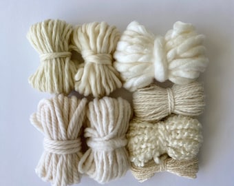 May include: Six spools of natural colored yarn in various textures, including a fluffy, chunky yarn and a smooth, thin yarn.