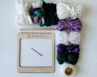 May include: A wooden loom with a needle and various balls of yarn in shades of white, purple, green, and a multi-colored yarn. The loom has the text "Stitched in Twine" printed on it.