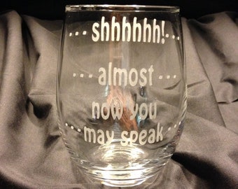 May include: A clear glass wine glass with the text "...shhh... almost... now you may speak..." etched on the side.