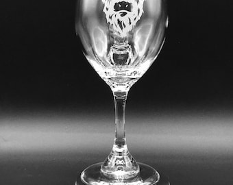 May include: A clear glass wine glass with an etched design of a Highland cow's head. The glass is on a silver pedestal.