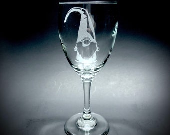 May include: A clear glass wine glass with an etched design of a gnome with a pointed hat and a beard.