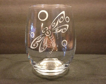 May include: A clear glass wine glass with an etched design of a dragonfly and circles.