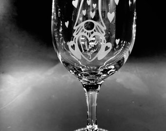 May include: A clear glass wine glass with an etched design of a gnome wearing a hat and holding a heart that says "I love you". The design is surrounded by small hearts.