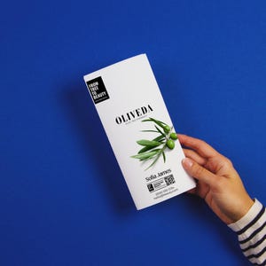 Może przedstawiać: Biała broszura z napisem "OLIVEDA" i gałązką oliwną na niebieskim tle. Broszura zawiera również tekst "FROM TREE TO BEAUTY" oraz imię i nazwisko "Sofia James".