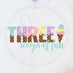 May include: A white t-shirt with the text "THREE scoops of fun" in colourful letters with ice cream cone graphics. The text is in a waffle cone pattern.