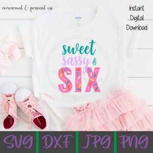 May include: A white t-shirt with a pink and white donut design that says "sweet sassy & six" in teal, purple, and pink lettering. The shirt is on a white surface with a pink tutu and pink sneakers.
