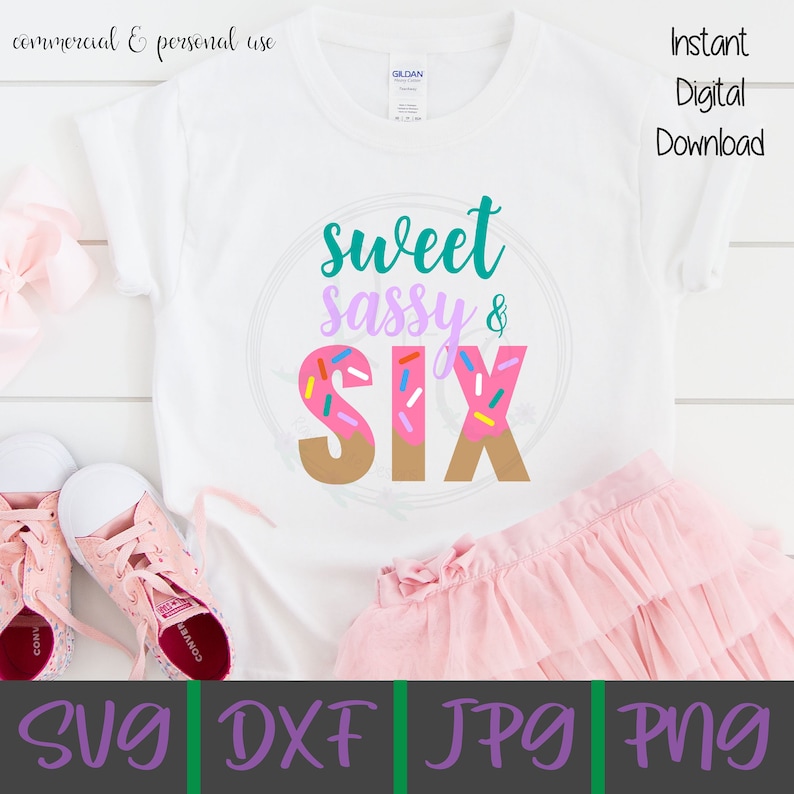 May include: A white t-shirt with the text "sweet sassy & six" in teal, purple, and brown. The number six is a pink donut with colorful sprinkles.