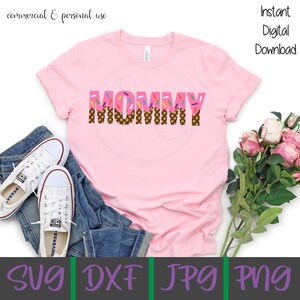 Puede incluir: Camiseta rosa con la palabra "MOMMY" en letras marrones y rosas con chispas en la parte superior. Las letras est&aacute;n dise&ntilde;adas para parecer conos de helado. La camiseta est&aacute; sobre un fondo blanco con un par de pantalones vaqueros azules y zapatillas blancas.