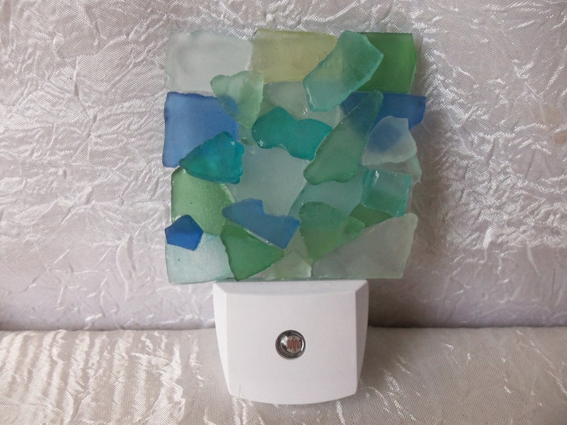 K&ouml;nnte beinhalten: Ein wei&szlig;es Nachtlicht mit einem klaren Glasschirm, der mit einem Mosaik aus Meerglas in Blaut&ouml;nen, Gr&uuml;n- und Wei&szlig;t&ouml;nen verziert ist.