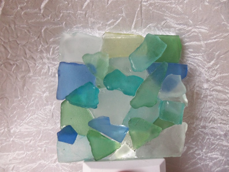 K&ouml;nnte beinhalten: Ein Nachtlicht aus Meerglas in Blaut&ouml;nen, Gr&uuml;n und Wei&szlig;. Die Glasst&uuml;cke sind in einem Mosaikmuster angeordnet.