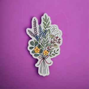 May include: A sticker of a bouquet of flowers with a variety of colors, including yellow, blue, purple, and red. The flowers are drawn in a simple, whimsical style.