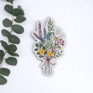 May include: A hand-drawn illustration of a bouquet of flowers in various colors, including yellow, red, purple, blue, and white. The flowers are tied together with a pink ribbon.