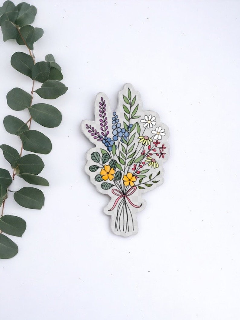 May include: A hand-drawn illustration of a bouquet of flowers in various colors, including yellow, red, purple, blue, and white. The flowers are tied together with a pink ribbon.