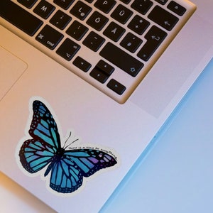 May include: A blue butterfly sticker with the text "there is a time for everything" on a silver laptop.