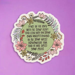 May include: A sticker with a floral wreath design. The sticker has a green center with the text "TRUST IN THE LORD WITH ALL YOUR HEART AND LEAN NOT ON YOUR OWN UNDERSTANDING: IN ALL YOUR WAYS ACKNOWLEDGE HIM. AND HE WILL DIRECT YOUR PATHS."