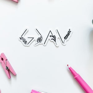 May include: A white sticker with the word "Grateful" written in black with a stylised arrow design and small floral accents.