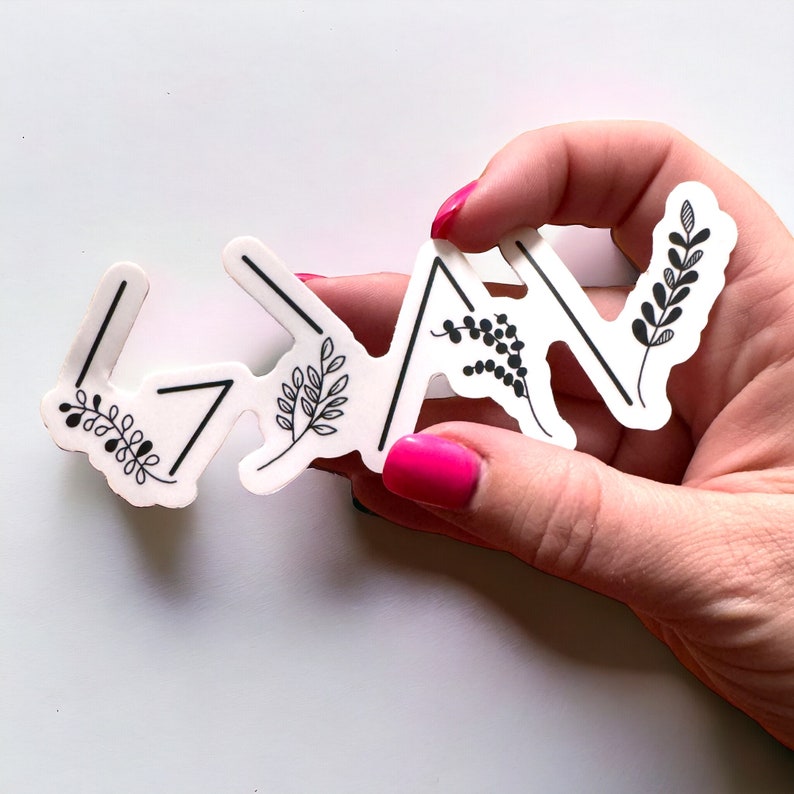 May include: White sticker with black arrows pointing upwards and small black floral designs. The sticker says "<3" in the centre.