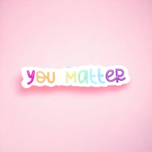 Op de afbeelding: Een witte sticker met de woorden "you matter" in regenboogkleuren op een roze achtergrond.