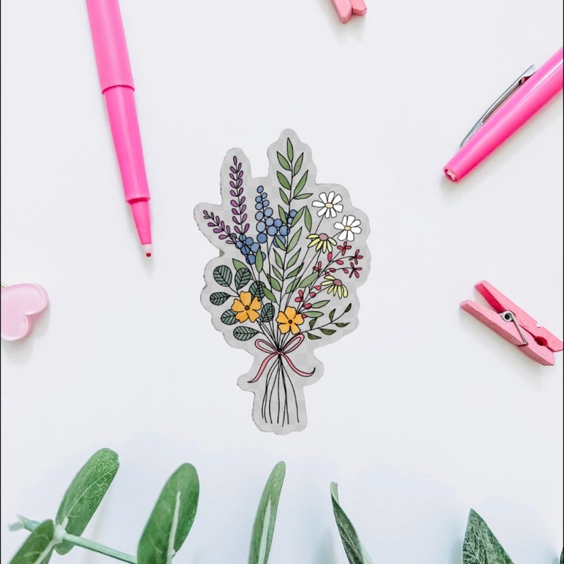 May include: A sticker featuring a hand-drawn bouquet of flowers in shades of blue, yellow, red, and green. The flowers are tied together with a pink ribbon.