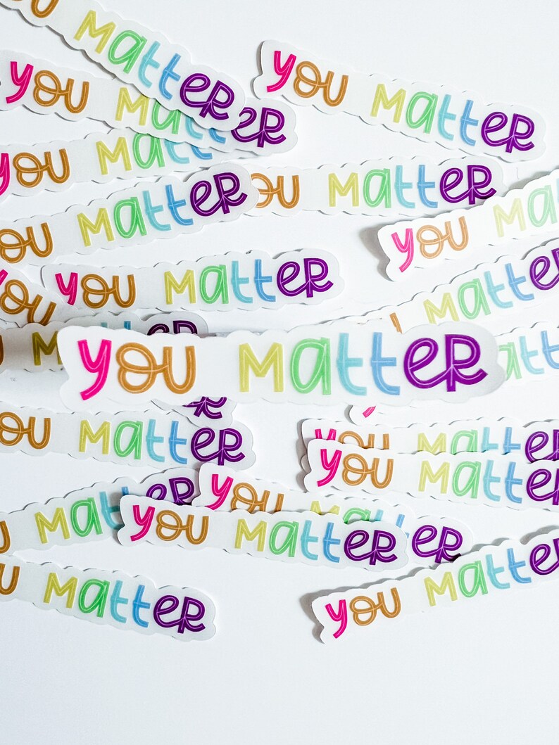 Op de afbeelding: Een verzameling kleurrijke stickers met de tekst "You Matter" erop. De stickers zijn willekeurig gerangschikt op een witte achtergrond.