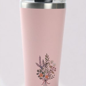 May include: A pink stainless steel travel mug with a black lid and a floral design. The design features a bouquet of flowers with orange, yellow, and purple accents.