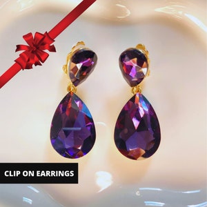 May include: A pair of clip-on earrings with two teardrop-shaped purple crystals on each earring.