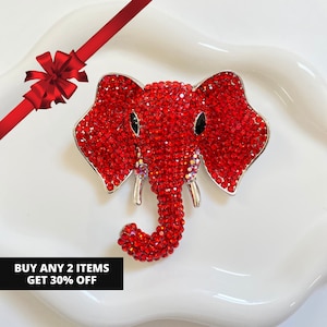 May include: A red rhinestone elephant brooch with silver-tone accents. The elephant has black eyes and a detailed trunk. The brooch is set against a white background. Text reads: BUY ANY 2 ITEMS GET 30% OFF.