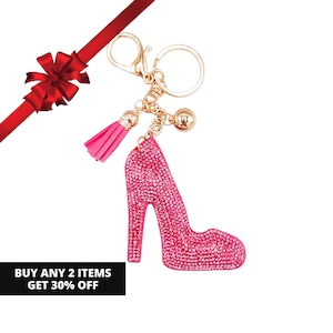 May include: A keychain featuring a high-heeled shoe charm covered in pink rhinestones, attached to a gold-tone metal ring and clasp. The accessory includes a small pink tassel and a gold-tone bead. Text reads: BUY ANY 2 ITEMS GET 30% OFF.