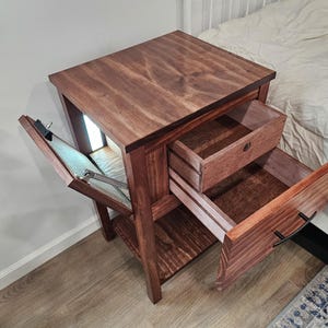 May include: A wooden nightstand with a hidden compartment, two drawers, and a shelf. The top drawer is open, revealing a dark wood interior. The nightstand is made of dark wood with a rich grain pattern.
