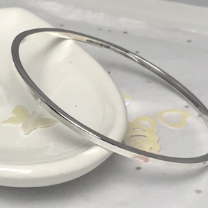 May include: A silver bangle bracelet with a smooth, polished finish. The bracelet is simple and elegant, and would make a great gift.