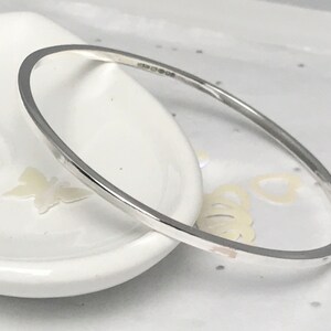 May include: A simple silver bangle bracelet with a smooth, polished finish.