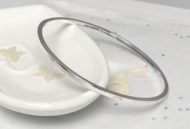 May include: A simple silver bangle bracelet with a smooth, polished finish.