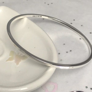 May include: A silver bangle bracelet with a smooth, polished finish.