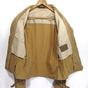 May include: A brown jacket with a beige lining and a small pocket on the left side. The jacket has a zipper closure and two pockets on the front. The jacket has a label on the inside that says "Y's for men".