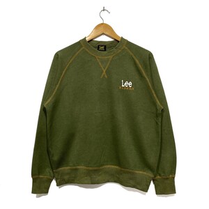 May include: A green long-sleeve sweatshirt with a yellow stitched trim. The sweatshirt has a white embroidered logo that says "Lee Riders".
